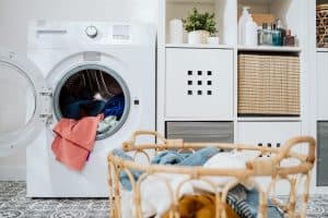 Close-up of colorful clothes in basket, open washing machine standing in background, weekend cleaning, household chores, laundry room