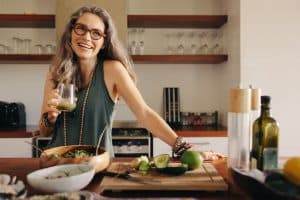 Healthy senior woman smiling while holding some green juice in her kitchen.